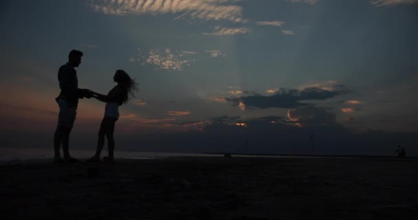 Silhouette von schönen Paar Händchen haltend. Zwei Menschen bei Sonnenuntergang. Silhouette gegen den Himmel geschossen, schöner Sommerabend — Stockvideo