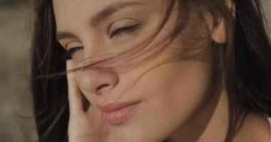 Huzurlu günbatımının tadını çıkaran güzel bir kadının portresi. Rüzgâr saçlara esiyor