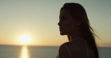 Huzurlu deniz ufkunun keyfini çıkaran güzel bir kadının portresi. Rüzgâr saçlara esiyor. 4K atış.