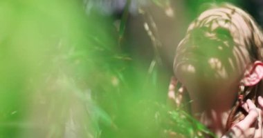 Yeşil ağaç dalları arasında yeşil gözlü güzel bir kız. Güzel kızların gözlerindeki büyüleyici bakış. Neşeli gülüşü ve güzelliğini vurgulayan aksesuarları olan genç ve güzel bir kadın. Kız.