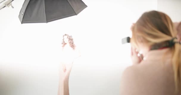 Modelo posando en el sutdio. fotógrafa toma una foto de la señora en vestido de noche rosa de pie sobre el fondo blanco — Vídeos de Stock