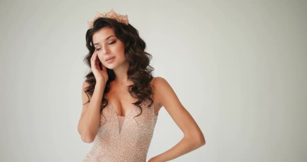 Model posing in the studio. Closeup of a woman in a golden crown looking straight in the camera while she poses in the white studio — Stock Video