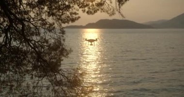 Gün batımında dağlarla çevrili güzel okyanusun üzerinde uçan helikopterin yakın çekim görüntüsü. 4 bin. Güzel doğa manzarası.