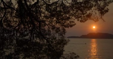 Gün batımında dağlarla çevrili okyanusun güzel doğa manzarası. Katamaran okyanus boyunca yüzüyor..