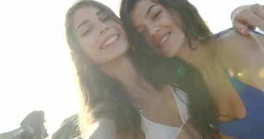 Tatildeki iki güzel kızın portresi. Sahilde mutlu bir şekilde selfie çekiyorlar. Yakın çekim görünümü.