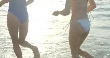 Bikinili iki beyaz kız arkadaşın kıyı boyunca aktifçe koştuğunu gördüm. Yüzü yok.