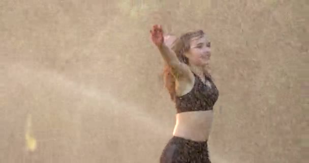 Bailarina bajo la lluvia. La seductora chica caucásica joven se divierte mientras gira y corre al aire libre. — Vídeo de stock