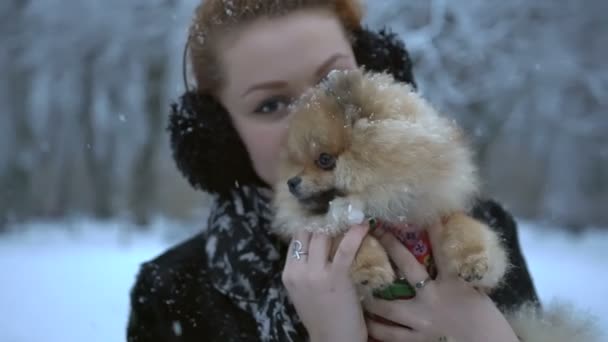 Retrato de la encantadora mujer besándose y jugando con su encantador spitz esponjoso de pomerania durante la nevada. — Vídeos de Stock