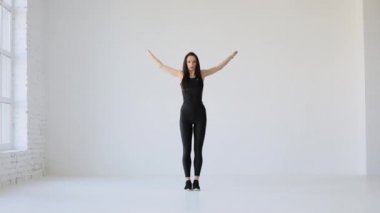 Spor ve Sağlık konsepti. Pilates ve Fitnes dersleri. Genç atletizm antrenörü stüdyoda yel değirmeni kol rotasyonu yaparken ısınıyor..