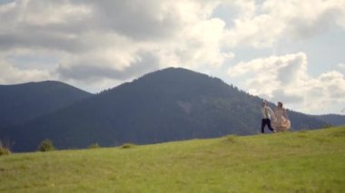 Büyüleyici klasik elbiseli çift, dağların arkasındaki yeşil çayır boyunca koşarken el ele tutuşuyorlar. Yakışıklı adam sevgilisini alıyor ve etrafında dönüyor..