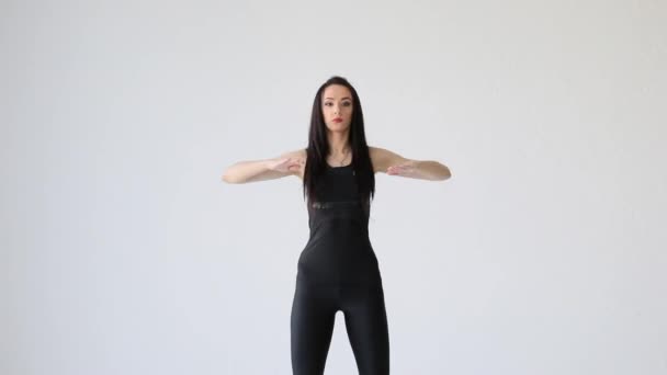 Retrato de la joven morena deportiva calentándose haciendo que el brazo se estire a cada lado en el fondo blanco. concepto de fitness y salud. — Vídeos de Stock