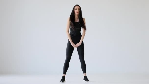 De fitness indoor tutorials. De atleet warmt zich op door het stretchen in de studio. De aantrekkelijke brunette is het aanraken van haar tenen en vloer. — Stockvideo