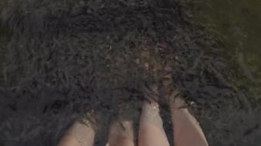 Garra Rufa balığıyla dolu suda iki çift çıplak kadın ve erkek ayağının üzerinde..