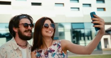 Güneş gözlüklü, dışarıda selfie çeken mutlu çiftin yan görüntüsü. 4k görüntü.