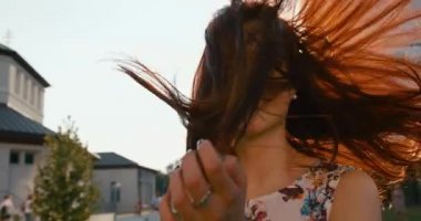 Çekici gülüşü olan mutlu, duygusal esmer güneş ışığında yürüyor ve dönüyor. İşaret fişeği. 4k.