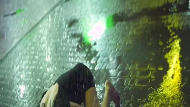 La joven hermosa chica deprimida en vestido negro con maquillaje untado está llorando y sentada en la calle durante la lluvia por la noche. — Vídeos de Stock