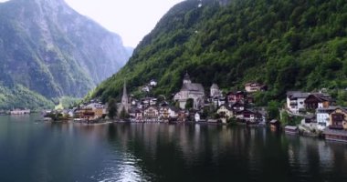 Avusturya 'daki Hallstatt Gölü yakınlarındaki Salzkammergut Dağları' ndaki küçük Hallstatt köyü ve binaları üzerinde uçan helikopterin yakın görüntüsü. 4k.