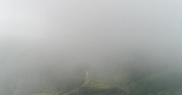 Volando helicóptero a través de las nubes que cuelgan sobre el hermoso paisaje de las montañas cubiertas de bosques gruesos. — Vídeos de Stock