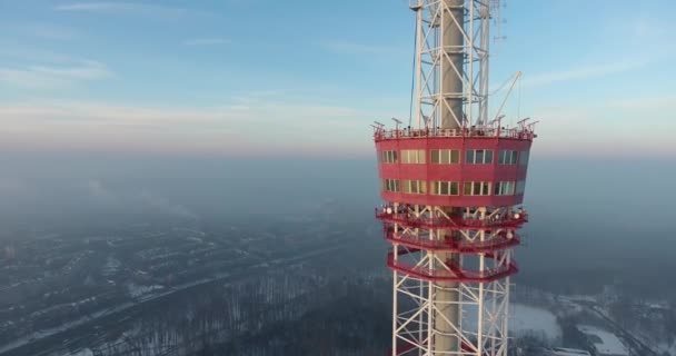 Vuelo aéreo del helicóptero volando desde la torre de televisión roja al fondo de la ciudad en invierno y hermoso cielo colorido durante la puesta del sol. — Vídeos de Stock