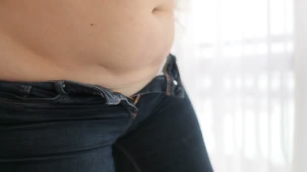 Wanita obesitas mengalami masalah dengan pencocokan dalam jins kecil. Masalah kesehatan dan berat badan. Tanpa wajah. — Stok Video
