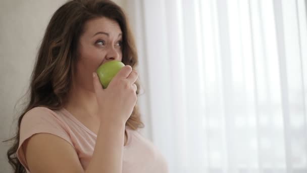 Die attraktive übergewichtige Frau mit grimmigem Gesicht isst einen Apfel, den sie auf Diät nicht mag. — Stockvideo