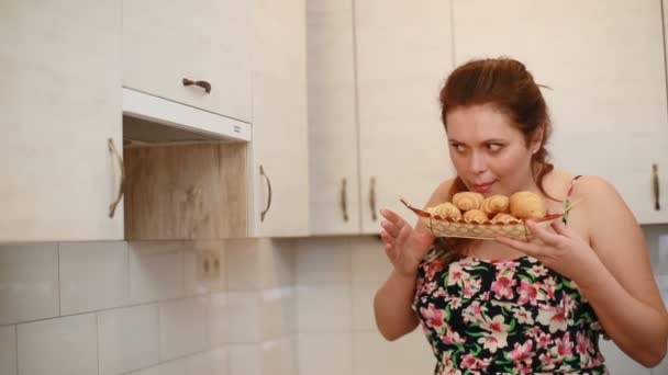La mujer con sobrepeso en la dieta está oliendo felizmente los sabrosos croissants y luego ponerlos en el gabinete de la cocina y con orgullo se va. — Vídeos de Stock