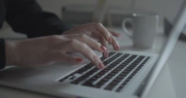 Ofisteki dizüstü bilgisayarında kırmızı tırnakları olan kimliği belirsiz iş kadınının yakın görüntüsü. Yüzü yok. 4k.
