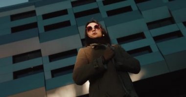 Modern cam inşaatından önce soğuk rüzgarda ayakta duran bir kızın kendini kucaklamasına bakın.