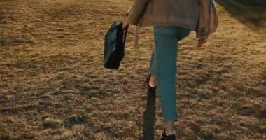 Arkadan atlayan genç kız öğrenciye bakın. Günbatımında modern cam binaya doğru yürüyor.