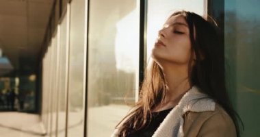 Çekici ve baştan çıkarıcı genç model cam kapıya eğilir ve doğrudan kameraya bakar.