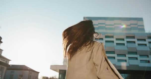 Vibras otoñales. Bastante joven estudiante sacude su cabello de pie ante la construcción de vidrio moderno en los rayos del sol de la noche — Vídeos de Stock