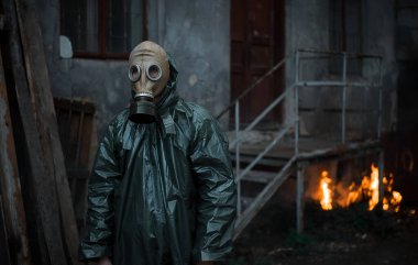 Koruyucu giysi ve gaz maskeli bilim adamı dozimetrist radyasyon danışmanı tehlike bölgesini araştırıyor. Ateş