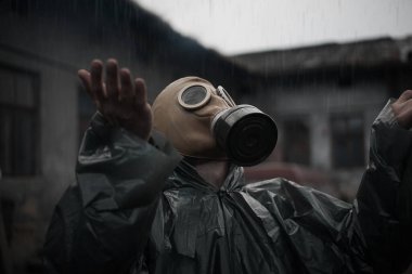 Koruyucu giysi ve gaz maskeli bilim adamı dozimetrist radyasyon danışmanı tehlike bölgesini araştırıyor. Yağmur. Yakın plan.