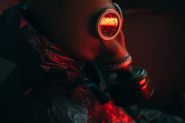 Scientist dosimetrist radiation supervisor in protective clothing and gas mask explores the danger zone. Rain. Red. Close-up