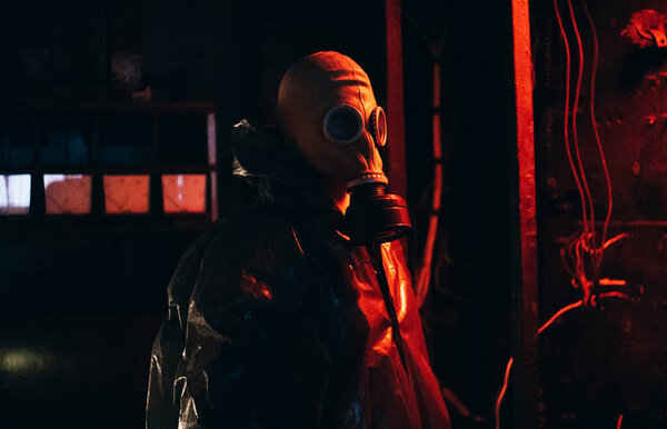 Scientist dosimetrist radiation supervisor in protective clothing and gas mask explores the danger zone. Rain. Red.
