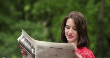 Parkta gazete okuyan güzel bir kadın. 4K video.