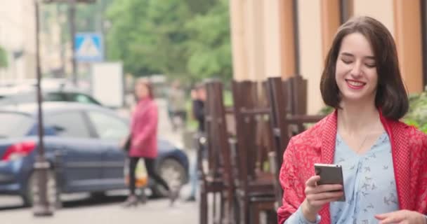 Close-up portret van aantrekkelijke vrouw met telefoon in handen. Een glimlachende brunette vol zelfvertrouwen. 4K-video. — Stockvideo