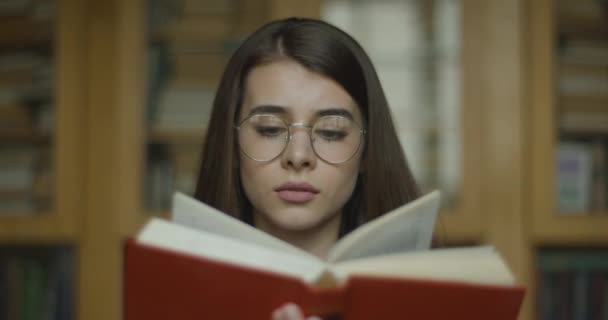 Femeie studentă, bibliotecă. O tânără studentă citește o carte — Videoclip de stoc