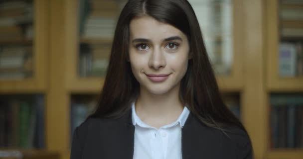 Vrouwelijke student, bibliotheek. meisje kijkt recht in de camera en glimlacht — Stockvideo