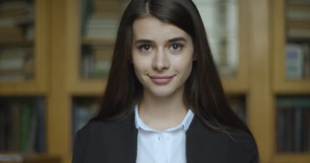 Estudante, biblioteca. Menina olha direto na câmera e sorri — Vídeo de Stock