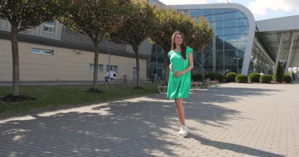 Attraktive mulher grávida feliz em um belo vestido andando. Conceito de gravidez. Menina grávida à espera do nascimento de um bebê, andando ao ar livre. — Vídeo de Stock