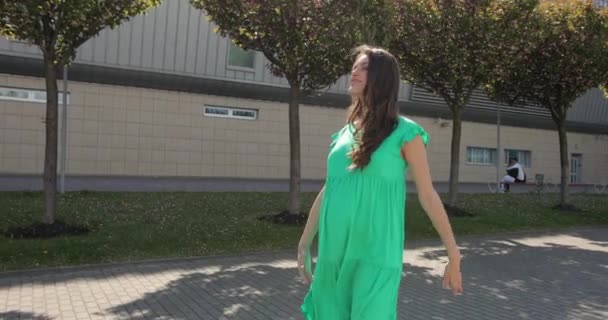 Όμορφη νεαρή έγκυος γυναίκα χαμογελά αισθάνονται ευτυχισμένοι με τα πόδια στο δρόμο. Έγκυος όμορφη γυναίκα σε ένα πράσινο φόρεμα. Κλείσε. Αργή κίνηση. — Αρχείο Βίντεο