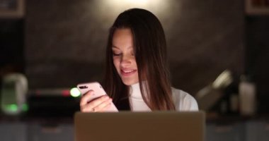 Genç ve çekici bir iş kadını, telefonda ve laptopta kullanıyor. Bir kadın bilgisayar başında çalışıyor ve elinde akıllı telefon tutuyor.