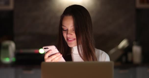 Jovem mulher de negócios atraente usando no telefone e laptop. Uma mulher está trabalhando em um computador e segurando um smartphone — Vídeo de Stock