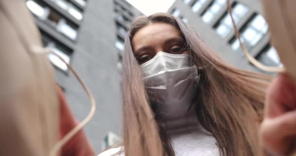 Mujer joven durante la pandemia con mascarilla médica abriendo la caja de cartón con pedido de la tienda de Internet, sintiéndose emocionada de recibir regalo — Vídeos de Stock