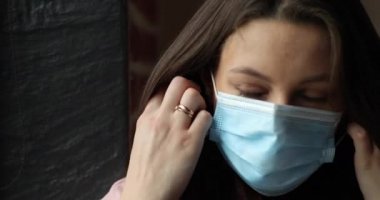 Çekici bir genç kadının yakın plan portresi. Güzel bir gülümsemesi var. Yüzündeki koruyucu tıbbi maskeyi çıkarıyor.