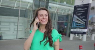 Çekici genç bir kadın tren istasyonuna ya da havaalanına gider ve telefonda konuşur..