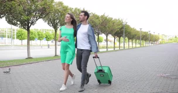 Vrouw en man lopen met bagage. Aankomst of vertrek naar een nieuw land. Paar wandelingen door de straat met bagage in de hand en verkent de stad — Stockvideo