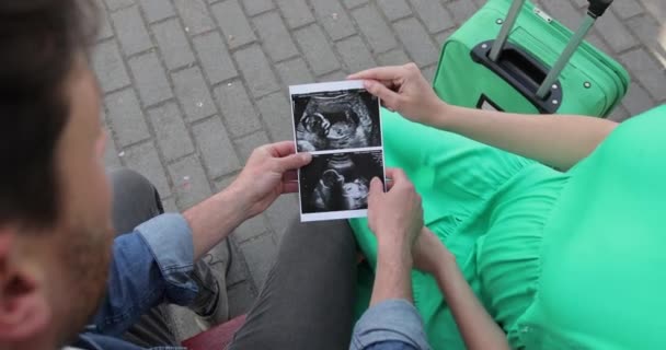 Young beautiful pregnant woman showing an ultrasound image to her husband. A couple in love is expecting a baby — Stock Video