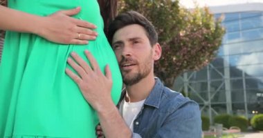 Adam hamile karısına gelir. Ellerini karnına koyuyor. Hamilelik ve mutlu evlilik kavramı.